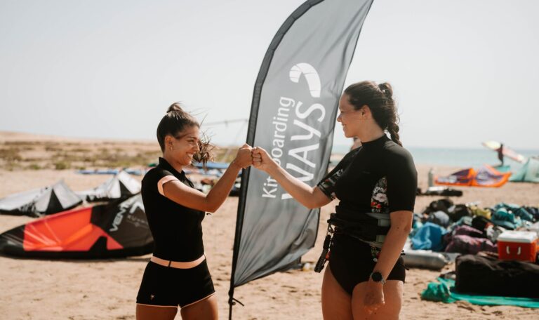 Two kitesurfers fist bumping on the beach during one-week kite safari in El Gouna